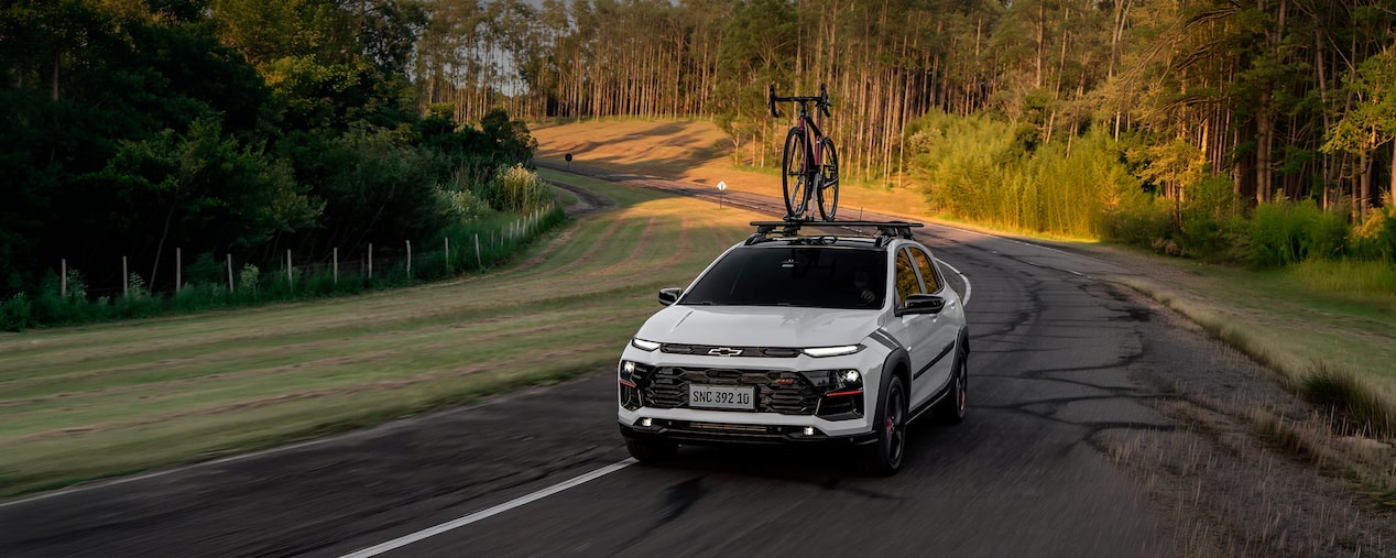 Vista superior del Chevrolet Sonic circulando por una ruta equipado con un porta bicicleta con vegetación de fondo.