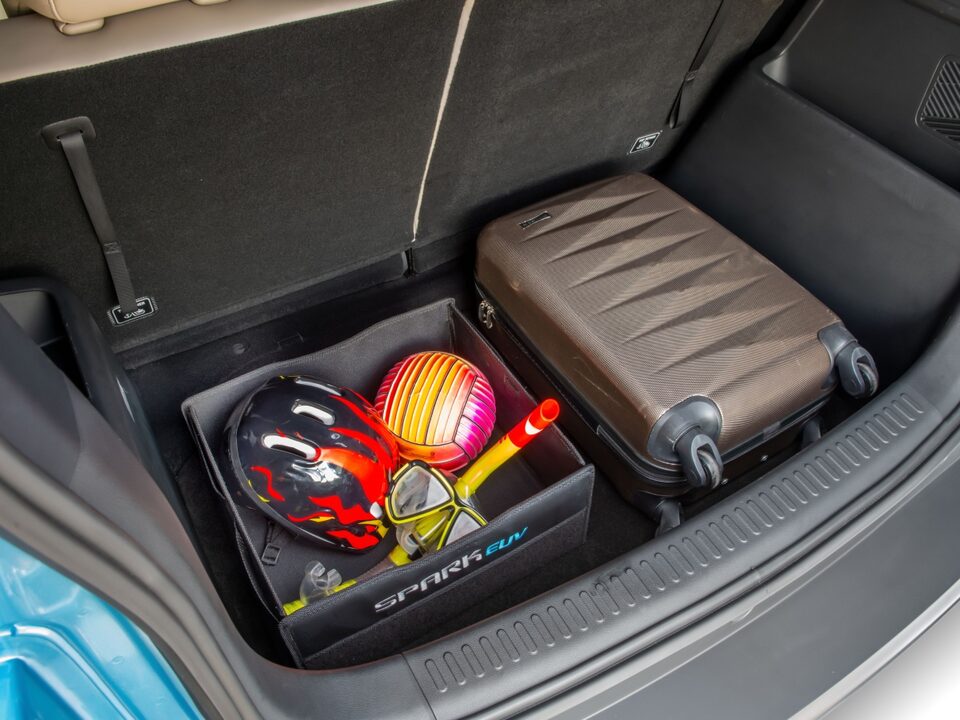 Porta-malas do Chevrolet Spark EUV com mala de bordo e organizador dobrável contendo equipamentos de praia, como máscara de mergulho, snorkel e bola inflável.