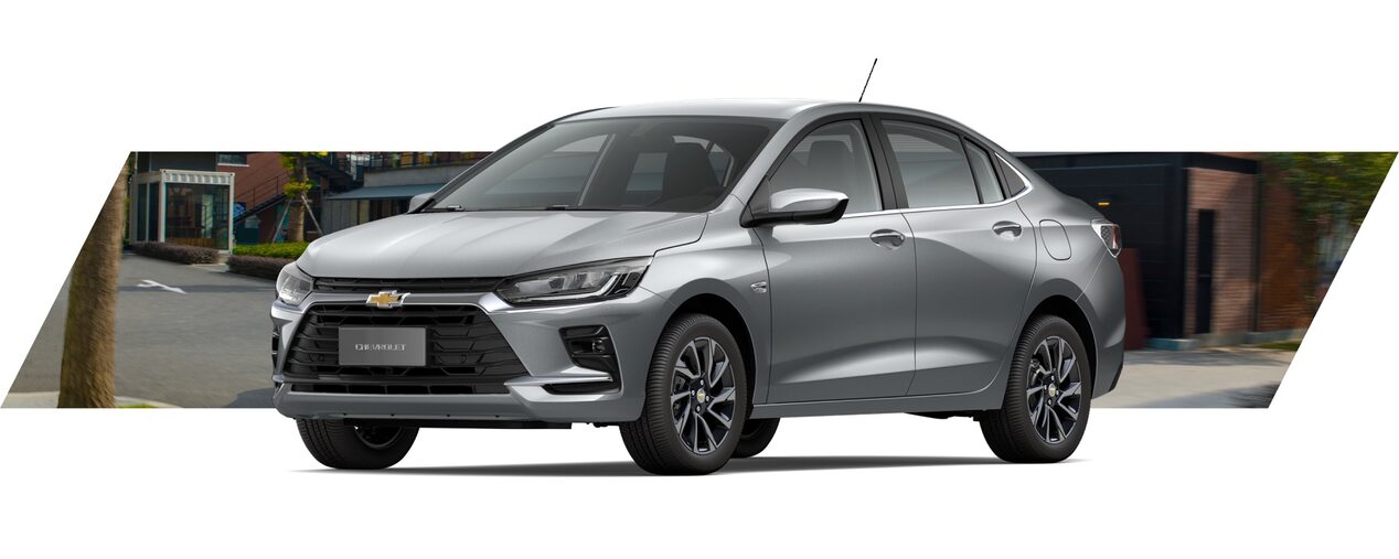 Onix Plus em vista de frente e lateral, com fundo urbano desfocado e iluminação suave.