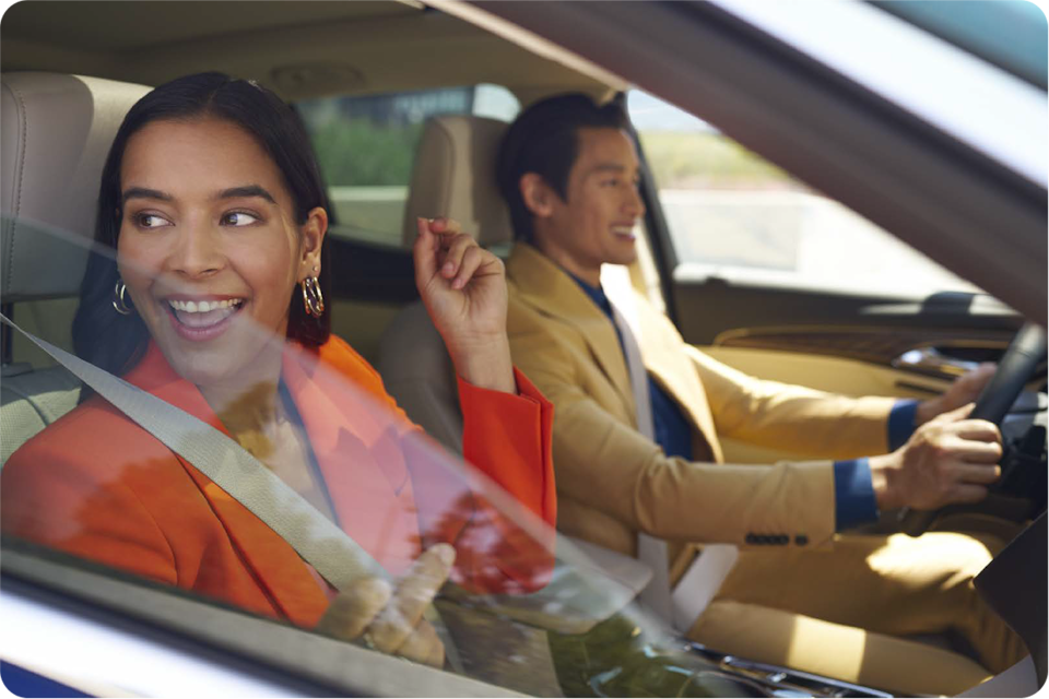 Casal sorridente dentro de um Chevrolet, com a mulher no banco do passageiro.