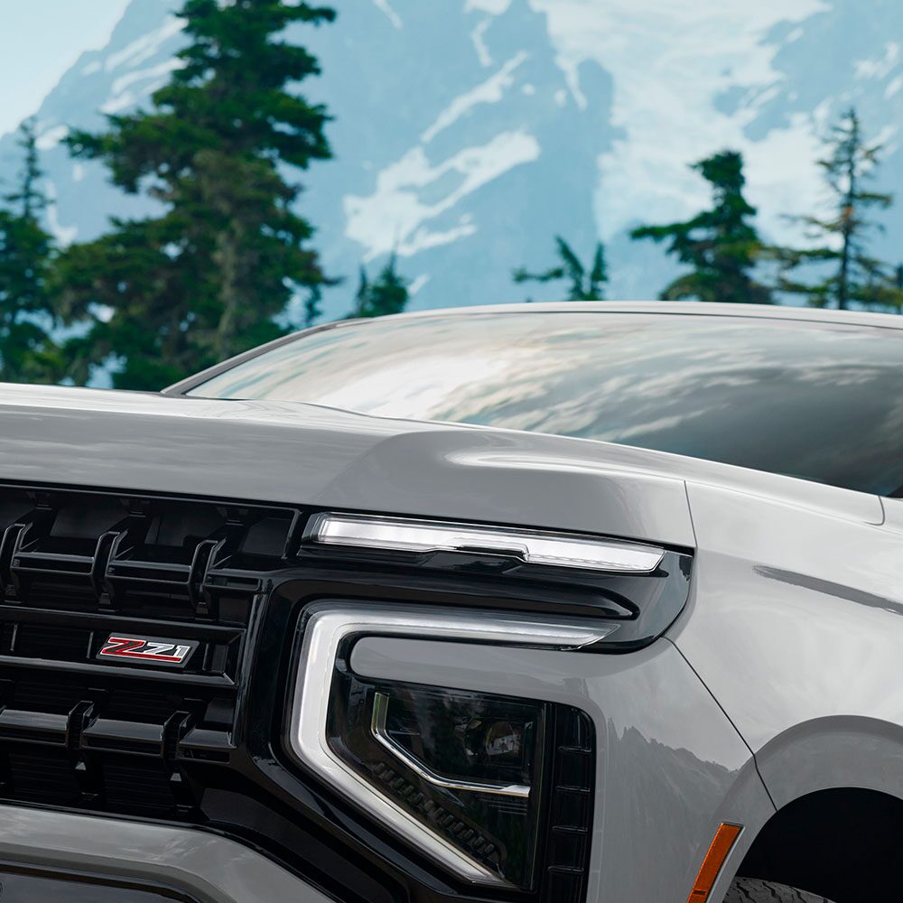 Chevrolet Suburban Z71 2025 vista frontal con detalle de parrilla negra, insignia Z71 y faros LED en entorno montañoso