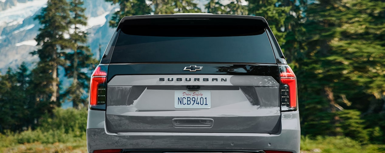 Vista trasera de Chevrolet Suburban SUV con paisaje montañoso de fondo.