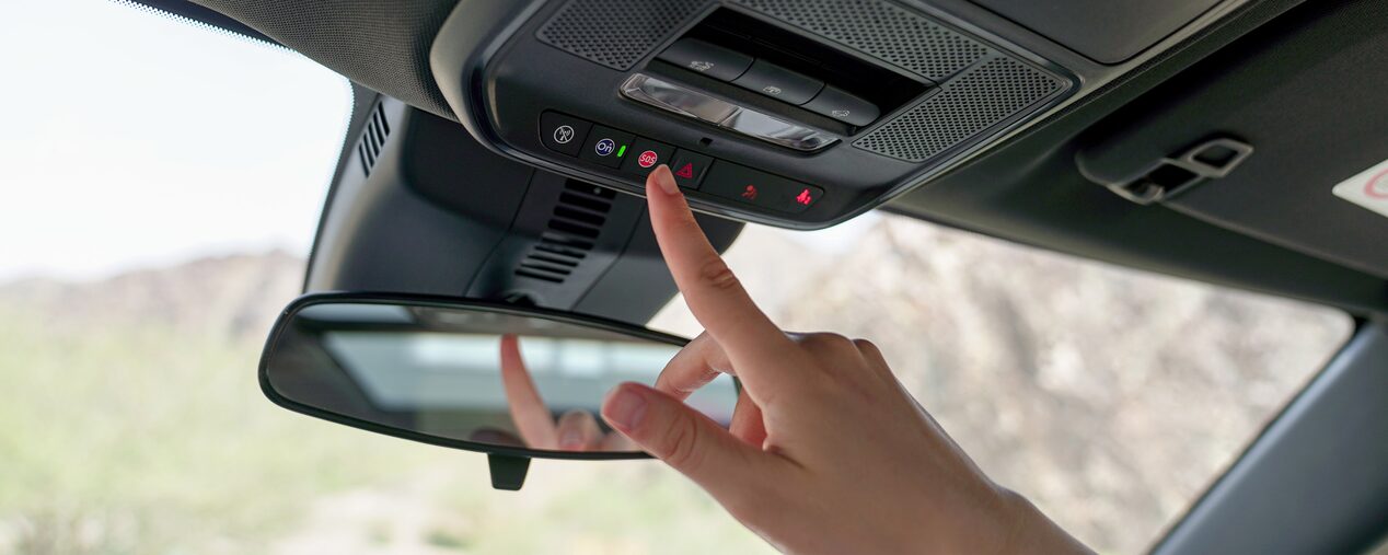 Persona presionando el botón OnStar de asistencia y emergencia en el interior de un vehículo Chevrolet