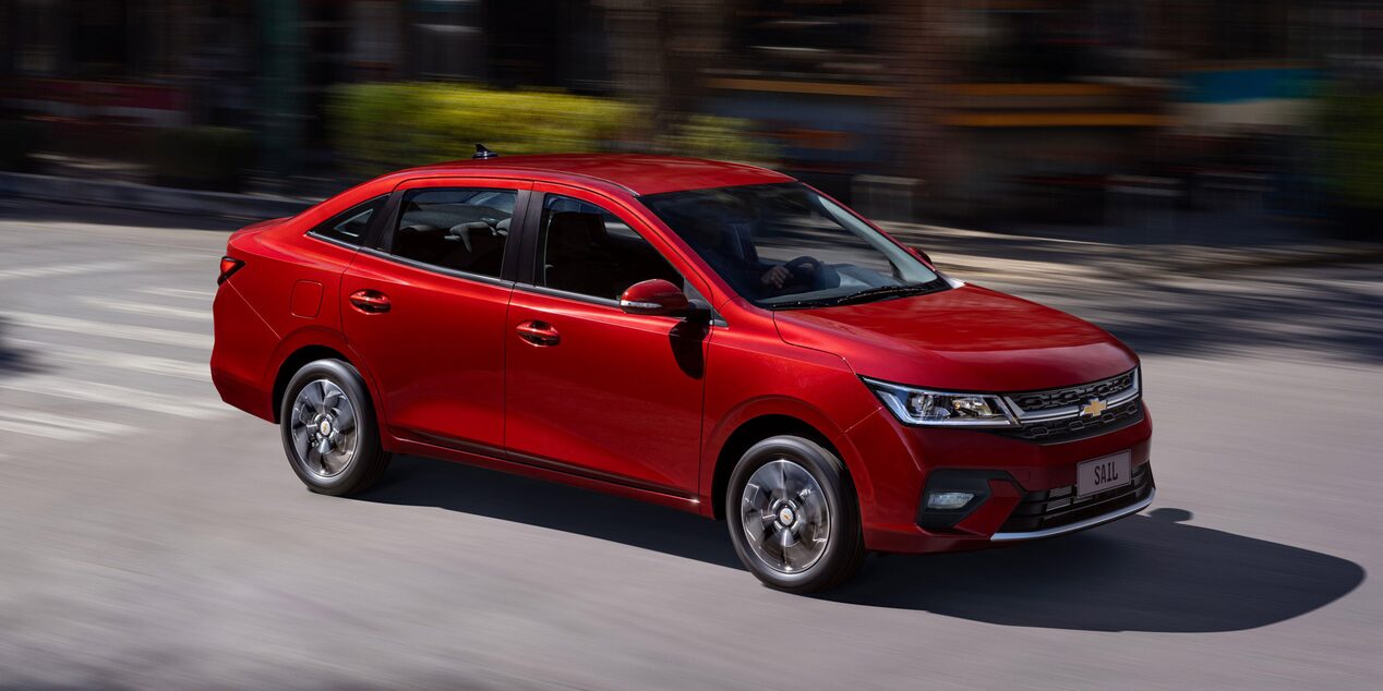 Vista lateral del Chevrolet Sail Sedán circulando por una calle en una zona urbana.