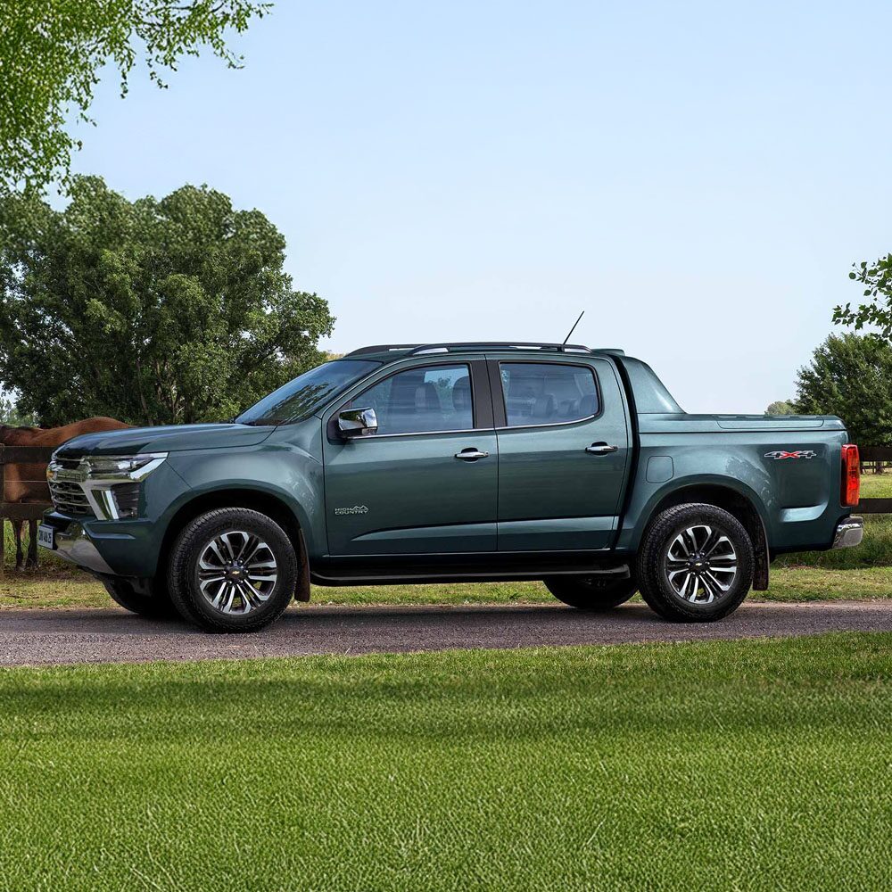 Chevrolet Colorado High Country estacioanada en el campo, con caballos y árboles al fondo.