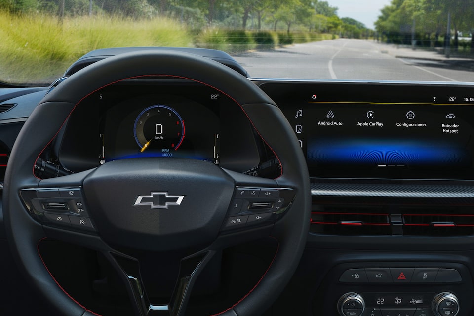 Interior del Chevrolet Onix Sedán 2026, mostrando el volante con el emblema de Chevrolet y una pantalla digital con conectividad y configuraciones del vehículo, destacando la tecnología e integración inteligente del modelo.
