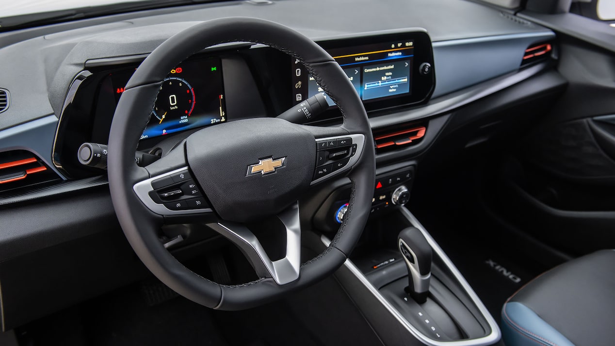 Interior del Chevrolet Onix Sedán, mostrando el volante, el tablero digital y la pantalla central táctil.