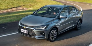 Chevrolet Onix Sedán circulando por una carretera rodeada de árboles.