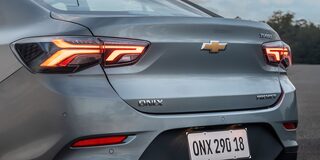 Vista trasera del Chevrolet Onix Sedán, destacando el baúl y los faros traseros con luces LED encendidas.