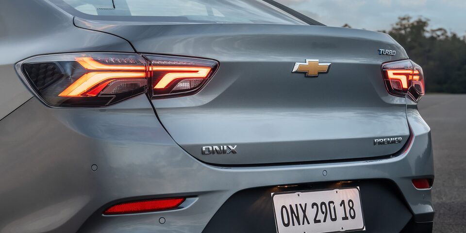 Vista trasera del Chevrolet Onix Sedán, destacando el baúl y los faros traseros con luces LED encendidas.