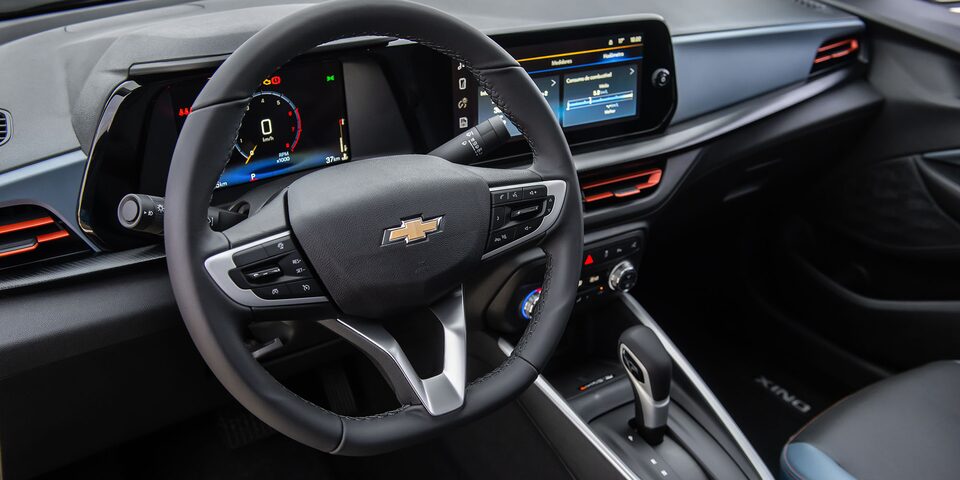 Interior del Chevrolet Onix Sedán Premier AT, mostrando el volante, el tablero digital y la pantalla central táctil con detalles en color azul y gris de ecocuero premium.