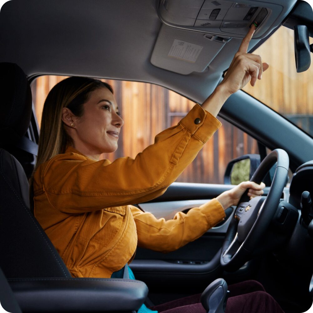 Mujer sentada en el asiento del conductor, utilizando OnStar desde su vehículo Chevrolet.