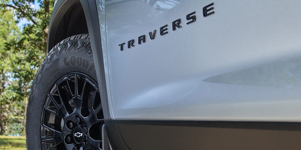 Vista en detalle de la insignia Traverse en la parte inferior izquierda del vehículo, junto a la llanta bitono.