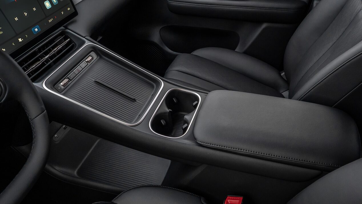 Vista interior de de la Chevrolet Captiva EV, destacando pantalla táctil, portavasos doble y apoyabrazos acolchado. .