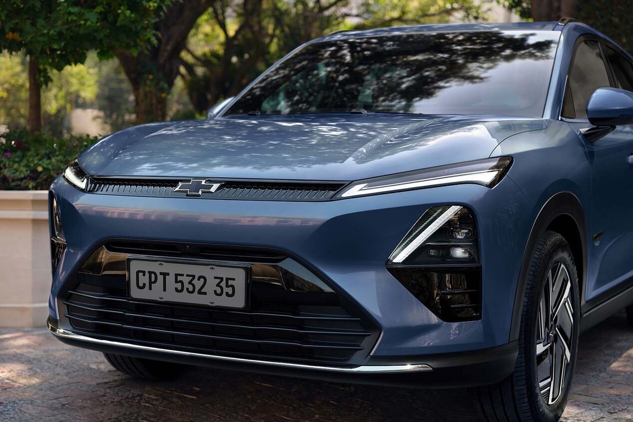 Vista frontal de la Chevrolet Captiva EV estacionada en zona urbana con vegetación de fondo.