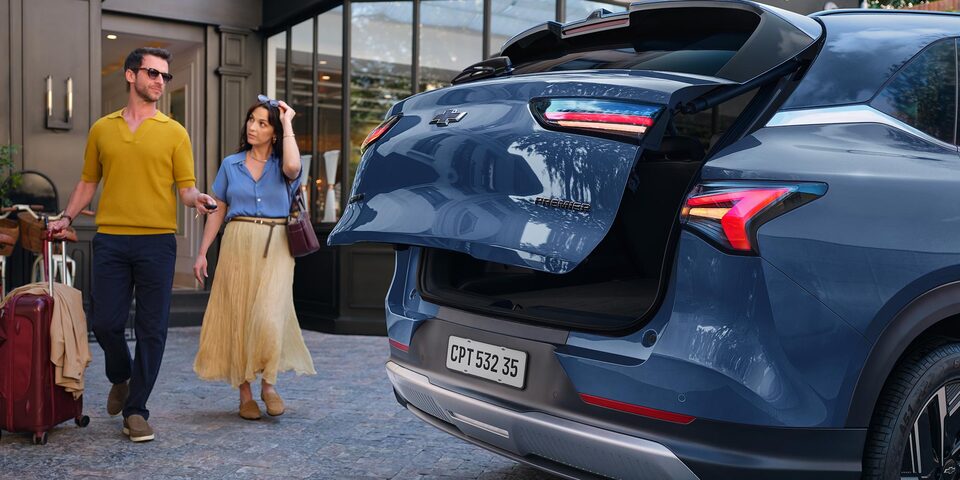 Una pareja acercandose a la Chevrolet Captiva EV para guardar sus pertenencias en el maletero.