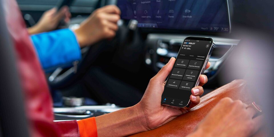 Persona usando la app móvil de Chevrolet para controlar funciones y seguridad del vehículo desde el interior del auto