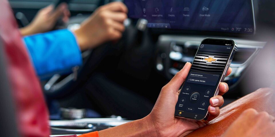 Persona usando la app móvil de Chevrolet para controlar funciones y seguridad del vehículo desde el interior del auto