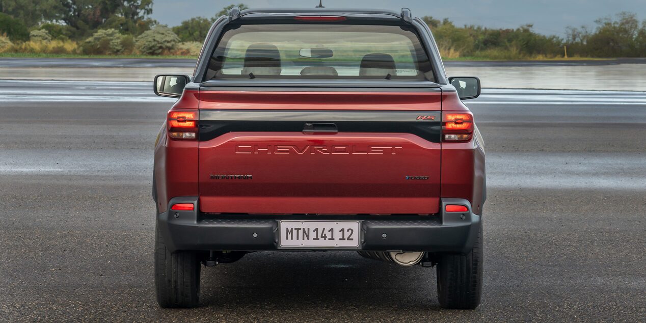 Vista lateral de una Montana Roja estacionada enfocando en el emblema de Chevrolet.