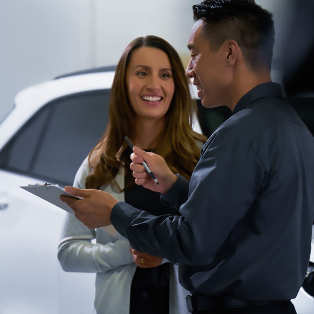 Imagen de un asesor Chevrolet hablando con una clienta, mietras sujeta una planilla y una lapicera.