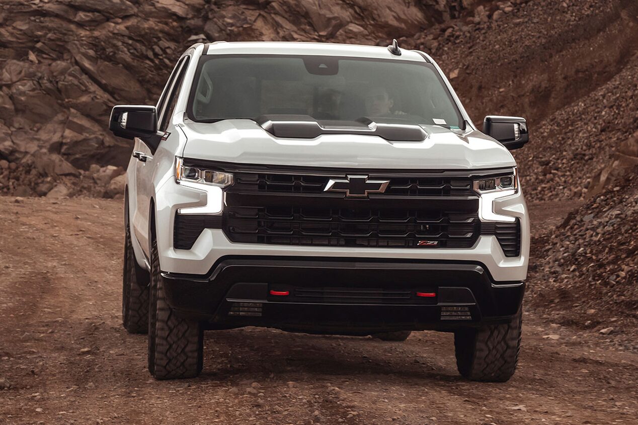 Vista frontal de la Chevrolet Silverado Z71 sobre camino de ripio, con árboles y montañas de fondo.