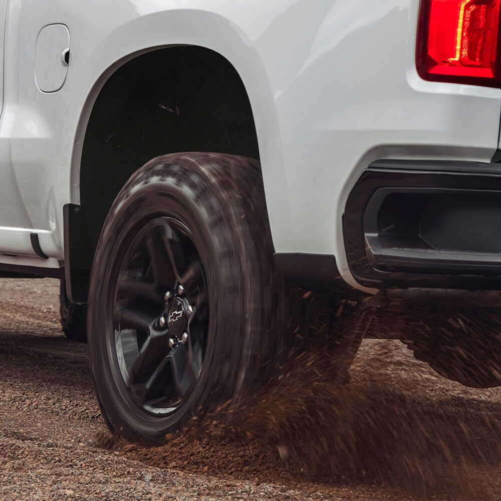 Vista trasera de la Chevrolet Silverado Z71 mientras una de sus ruedas traseras gira y levanta piedras.