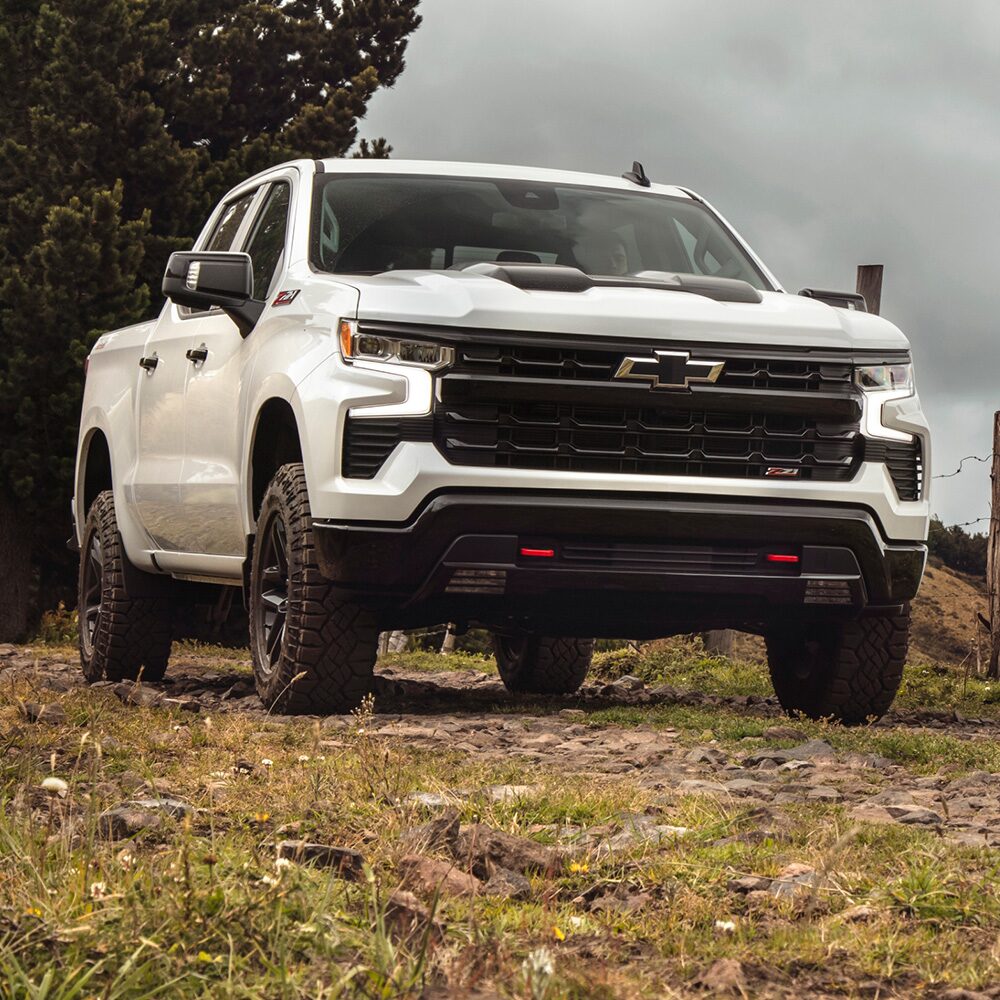Vista frontal de la Chevrolet Silverado Z71 sobre camino de ripio, con árboles y montañas de fondo.