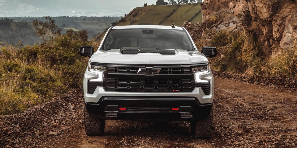 Vista frontal de la Chevrolet Silverado Z71 sobre camino de ripio, con árboles y montañas de fondo.