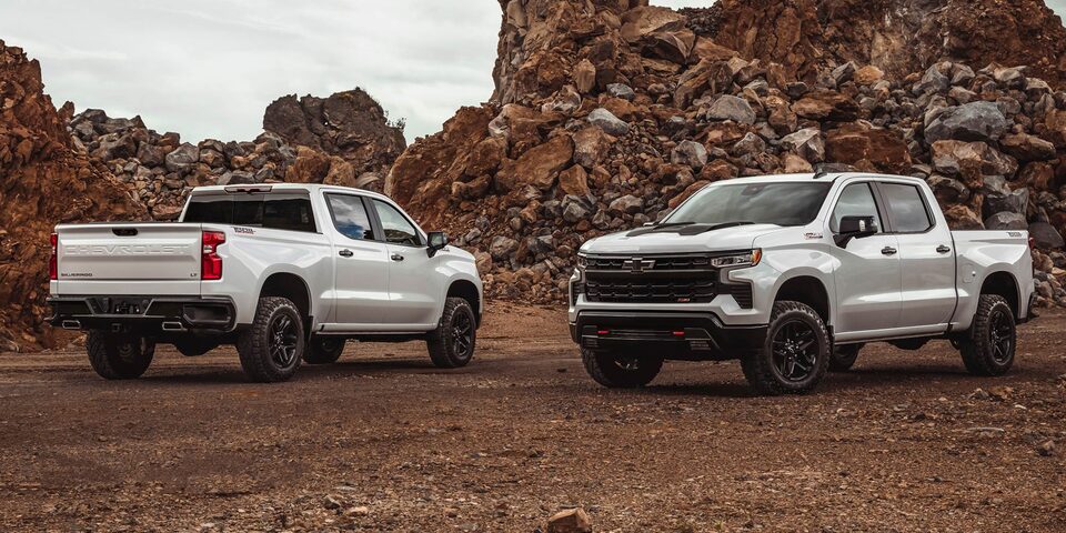 Vista trasera y vista frontal y de costado de la Chevrolet Silverado Z71, sobre un camino de ripio y con rocas detrás.