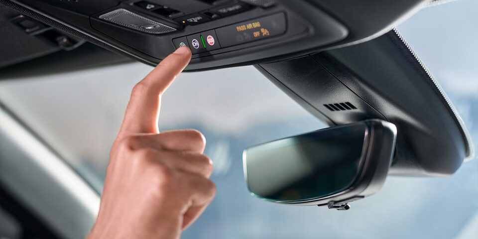 Primer plano de la mano de una persona activando el botón de OnStar en su vehículo Chevrolet.