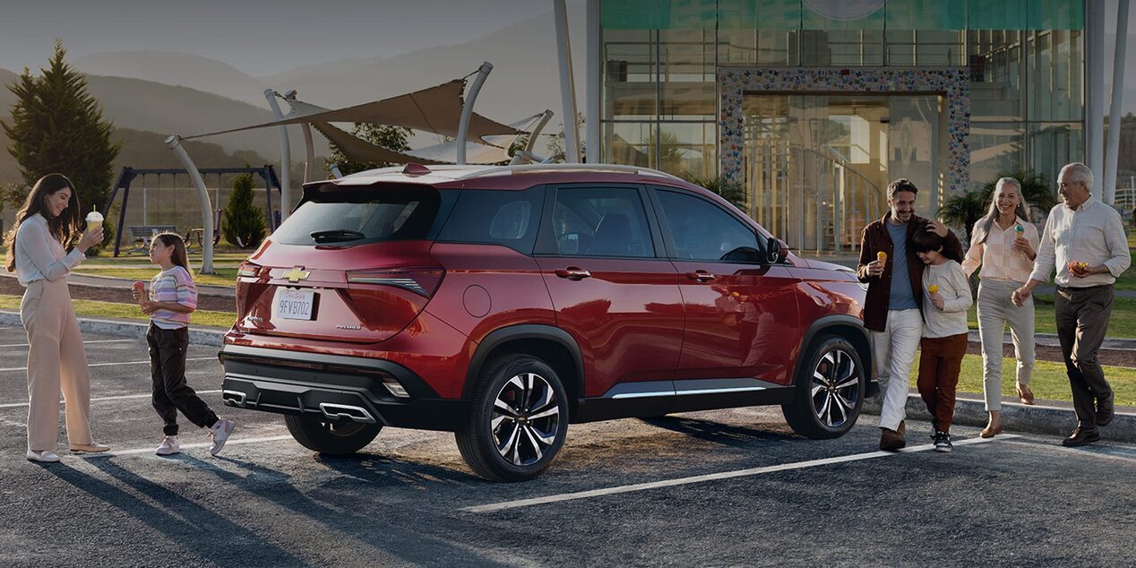 Chevrolet Captiva XL estacionada con una familia cerca.