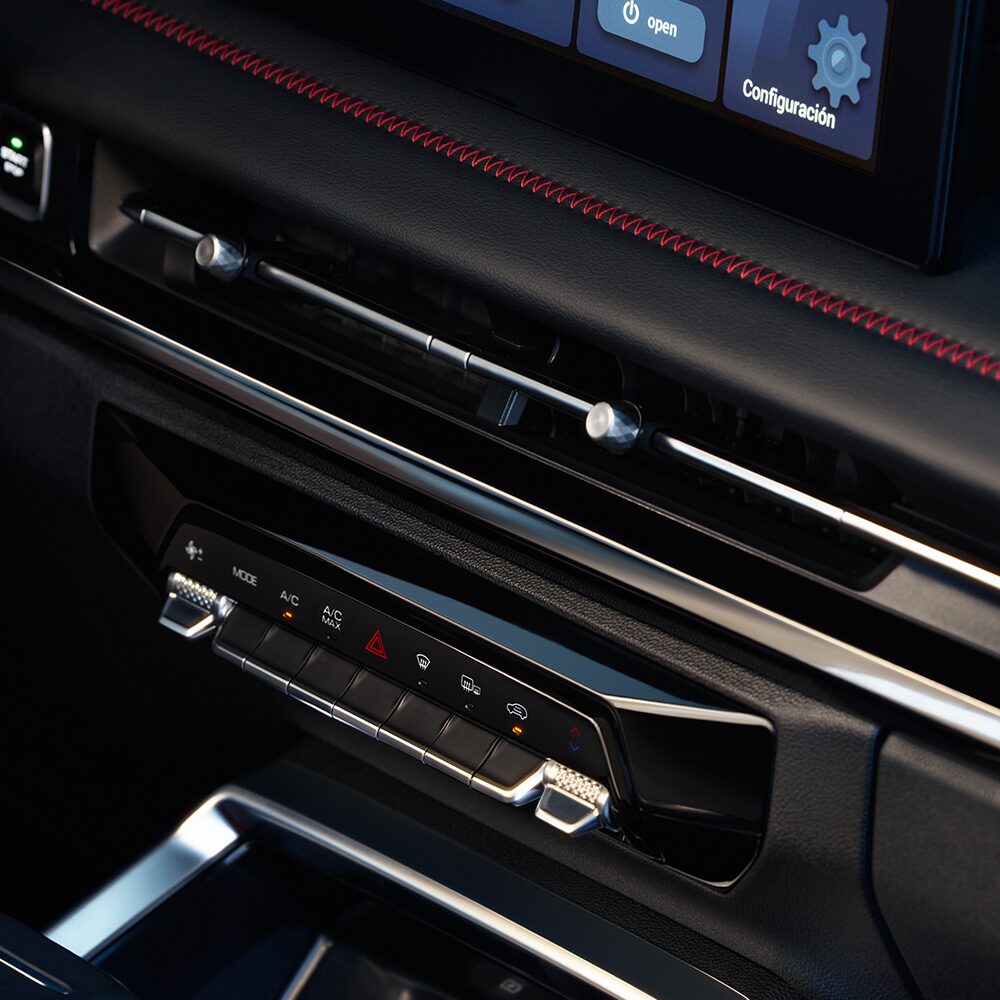 Controles del aire acondicionado digital de la Chevrolet Groove LTZ, con botones táctiles y detalles cromados ubicados bajo la pantalla central del sistema de infoentretenimiento.