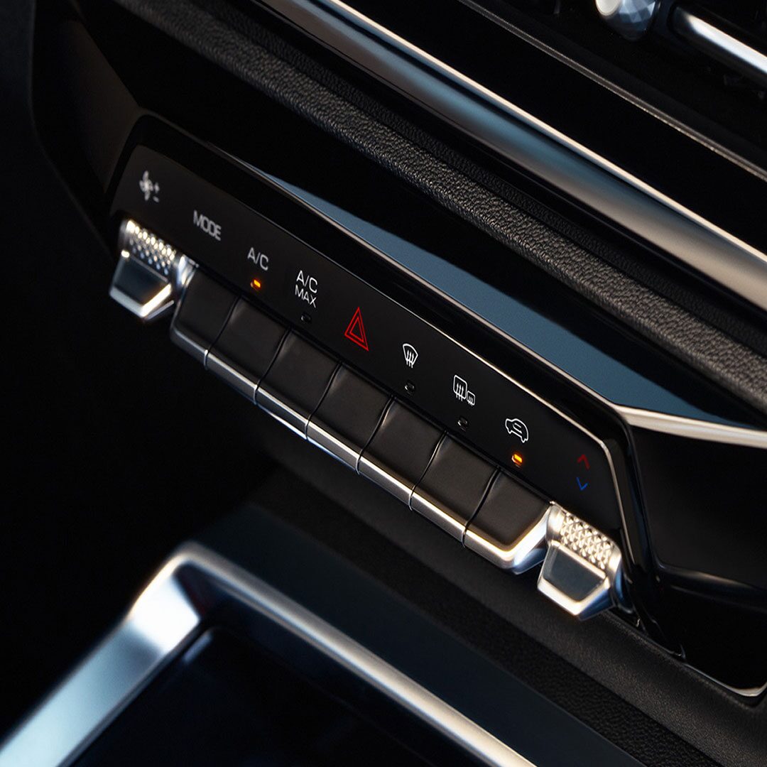 Controles del aire acondicionado digital de la Chevrolet Groove, con botones táctiles y detalles cromados ubicados bajo la pantalla central del sistema de infoentretenimiento.