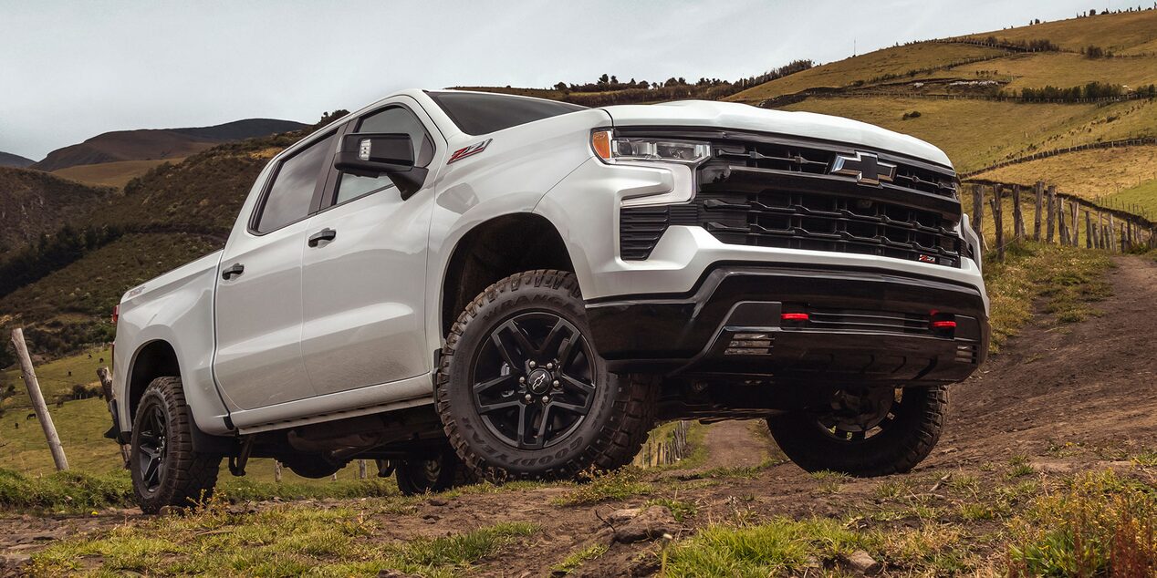 Imagen de una Chevrolet Silverado subiendo por un camino de tierra delimitado por un alambrado, on caballos y naturaleza de fondo.