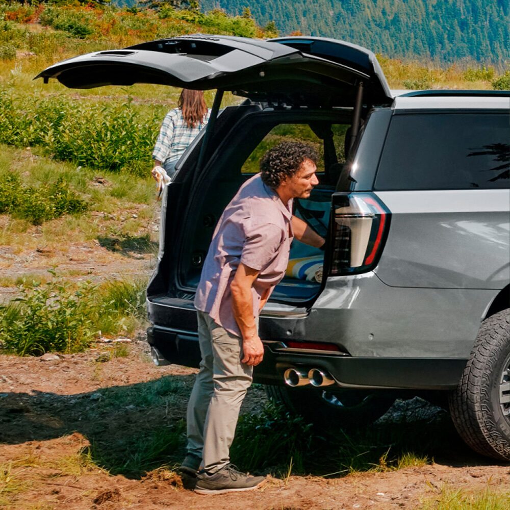 Hombre sacando cosas del baúl de la Chevrolet Suburban Z71.