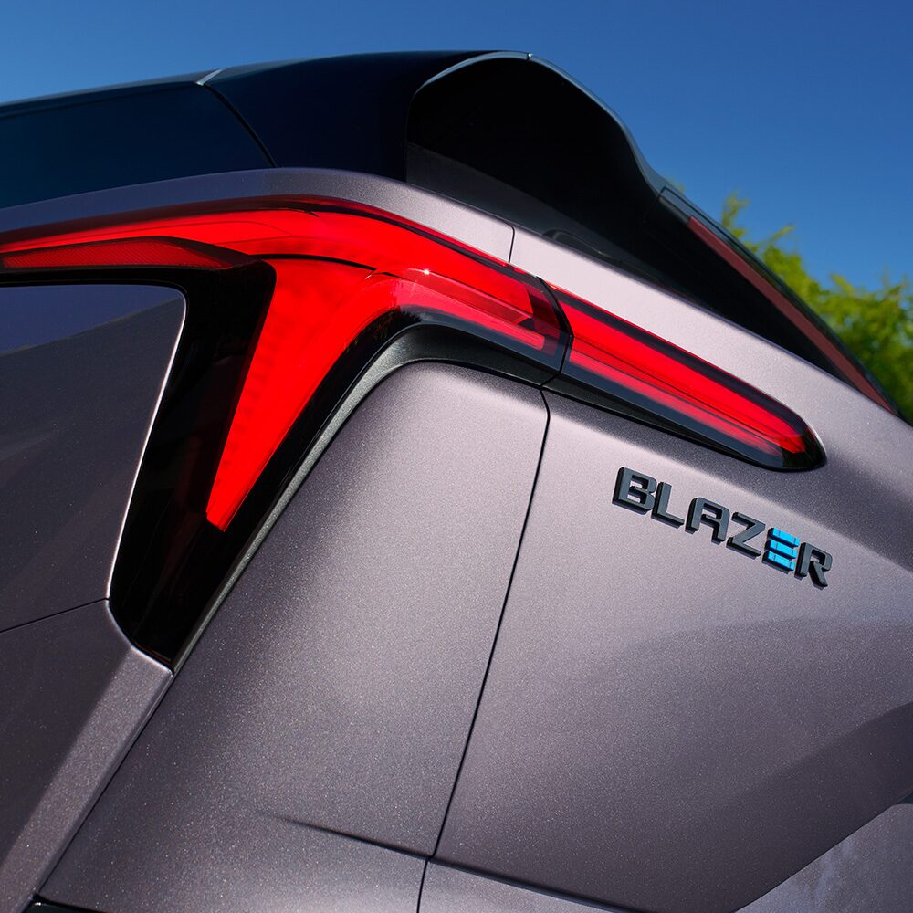 Imagen en detalle del faro trasero izquierdo junto a la insignia Blazer con la letra E en color azul.