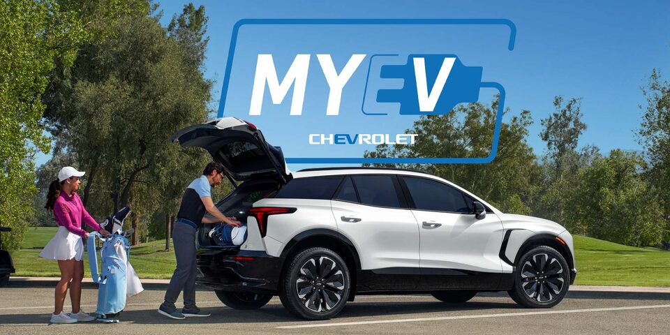 Una pareja cargando equipos de golf en el baúl de una Chevrolet Blazer EV, junto al texto de MY EV CHEVROLET en el centro de la imagen.